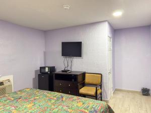 a bedroom with a bed and a tv on a wall at Vanguard Motel in Ormond Beach