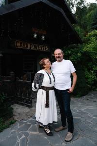 a man and a woman standing in front of a building at Casa Poveste Pensiunea-Muzeu in Câmpulung Moldovenesc