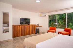 a bedroom with a bed and two chairs and a television at Gardin Home in Cali