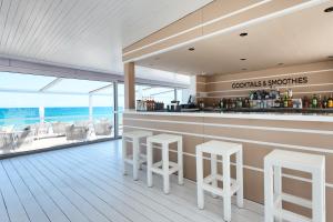 a bar with stools and a view of the ocean at Hotel Garbi Ibiza & Spa in Playa d'en Bossa