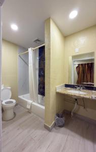 a bathroom with a toilet and a sink and a tub at Vanguard Motel in Ormond Beach