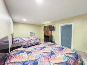 a bedroom with two beds and a television at Vanguard Motel in Ormond Beach