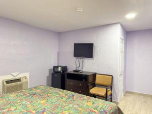a bedroom with a bed and a tv and a chair at Vanguard Motel in Ormond Beach