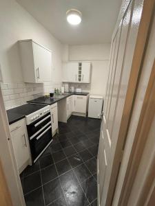 a kitchen with white cabinets and a black tile floor at One Bedroom flat in Doncaster Prime Location in Doncaster