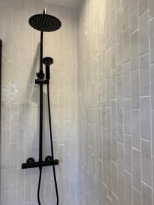 a shower with a white tiled wall with a shower at 5 Bed Cottage in Enfield