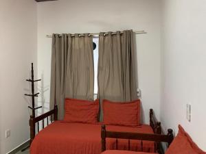 a bedroom with two beds with red pillows and a window at Casa Rebello - Pousada in Itajaí