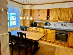 a kitchen with wooden cabinets and a wooden table at Myranhuset - Amazing View in Moskenes