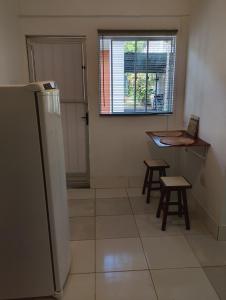 a kitchen with a refrigerator and a table and stool at Vereda da Lagoa in Niterói