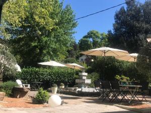 a patio with umbrellas and tables and chairs at HOTEL GALIMAR in Lamalou-les-Bains +6 photos
