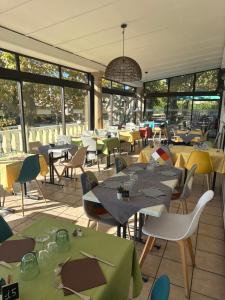 a restaurant with tables and chairs and windows at HOTEL GALIMAR in Lamalou-les-Bains