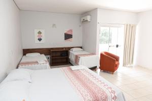 a bedroom with two beds and a chair and a window at San Felipe Hotel in Colinas do Tocantins +23 photos