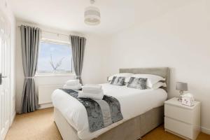 a white bedroom with a large bed and a window at Ocean Breeze - Stunning Harbour Views from Private Balcony in Poole