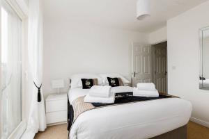 a white bedroom with a large bed with black and white pillows at Ocean Breeze - Stunning Harbour Views from Private Balcony in Poole
