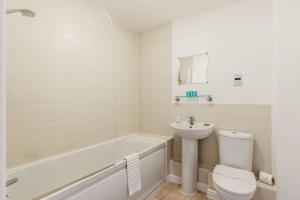 a white bathroom with a toilet and a sink at Ocean Breeze - Stunning Harbour Views from Private Balcony in Poole