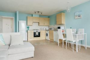 a living room with a white couch and a kitchen at Ocean Breeze - Stunning Harbour Views from Private Balcony in Poole