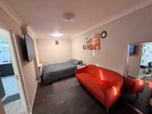 a living room with a red couch and a bed at Demure Living Space in Southampton