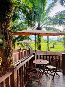 a table and chairs on a deck with an umbrella at Pudina Resort in Semporna +3 photos