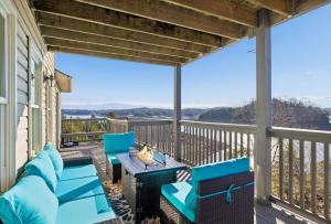 a porch with blue chairs and a table with a view at Lighthouse Lookout by Beyond Expectations - Hot Tub & Lake Views in Sevierville
