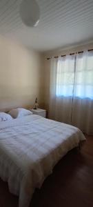 a bedroom with a white bed and a window at Le Village Champignon in Aspet