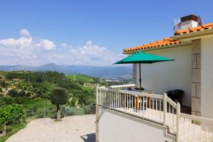 a balcony of a house with a green umbrella at Casa Fundevila Celorico de Basto in Celorico de Basto