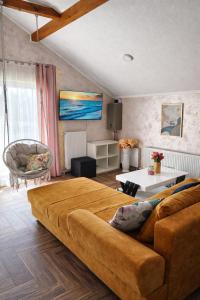 a living room with a couch and a table at Sunrise Riverside House-Private Garden, Jacuzzi & BBQ in Čelarevo