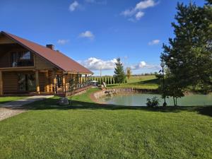 a log cabin with a pond in the yard at Vila Noruciai in Šašeliai