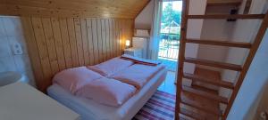 a small bed in a small room with a ladder at Dabki Village - Villa Rena in Dąbki