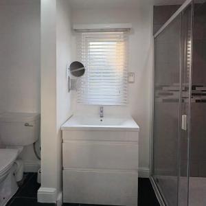a white bathroom with a sink and a shower at Santa's Cottage in Torquay