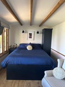 a bedroom with a blue bed and a chair at Swifts Return Shepherd's Hut in North Lopham