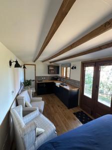a room with two chairs and a bed and a kitchen at Swifts Return Shepherd's Hut in North Lopham
