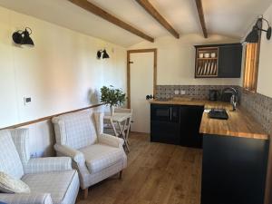a kitchen with two chairs and a table in a room at Swifts Return Shepherd's Hut in North Lopham