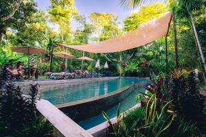 a swimming pool with umbrellas and tables and chairs at Kapievi Ecovillage in Puerto Maldonado