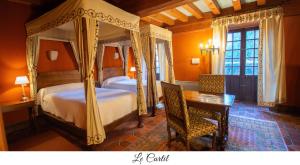 a bedroom with a canopy bed and a table and chairs at Hostellerie du Vieux Pérouges in Pérouges