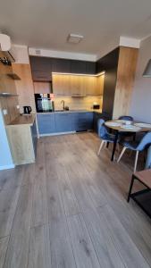 a kitchen with wooden floors and a table and chairs at Apartament Skarbowa East in Leszno