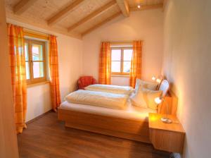 a small bedroom with a bed and two windows at Wimmerhof - Chiemgau Karte in Inzell