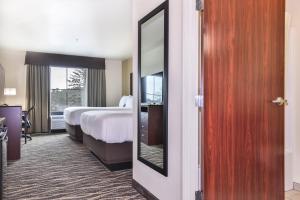 a hotel room with a bed and a mirror at Cobblestone Hotel & Suites - Monte Vista in Monte Vista