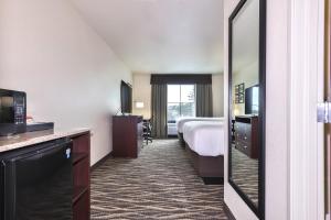 a hotel room with a bed and a mirror at Cobblestone Hotel & Suites - Monte Vista in Monte Vista