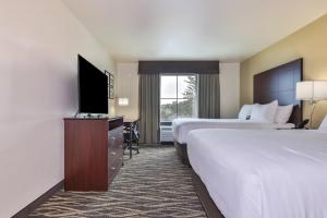 a hotel room with two beds and a flat screen tv at Cobblestone Hotel & Suites - Monte Vista in Monte Vista