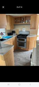 a kitchen with wooden cabinets and a black stove at Promenade Betty's in Ingoldmells