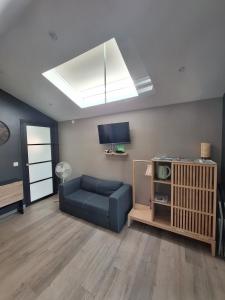 a living room with a blue couch and a skylight at Gîte des binamés in Profondeville