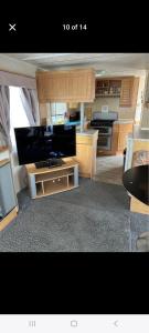 a kitchen with wooden cabinets and a large tv at Promenade Betty's in Ingoldmells