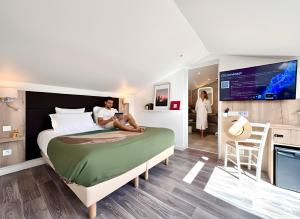 a woman sitting on a bed in a room at Hotel Le Provence - Restaurant Le Styx in La Palud-sur-Verdon