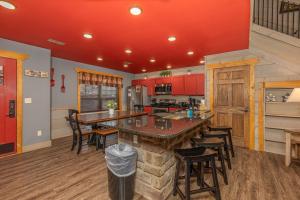 a kitchen with red cabinets and a large kitchen island at Bears Haven – Elegant 3 BR Chalet Game Area, Hot Tub, see through fire place in Gatlinburg