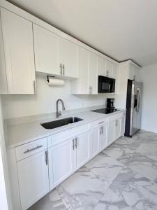 a white kitchen with a sink and a refrigerator at 2 bed peaceful, lakeview studio NO FEES in Atlantis +20 photos