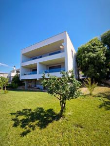 a white building with a tree in the grass at Providenca Residence Šibenik in Šibenik