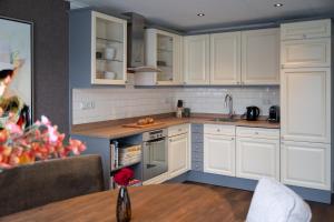 a kitchen with white cabinets and a wooden table at Suite Het Koetshuis in Bennekom