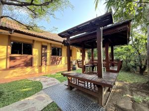 a wooden bench in front of a house at Yellow House Garden Pool Villa in Chiang Mai