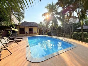 a swimming pool in front of a house with palm trees at Yellow House Garden Pool Villa in Chiang Mai