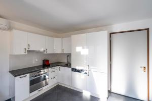 a white kitchen with white cabinets and a refrigerator at CENTRO Appartamento Ascona in Ascona +2 photos