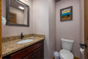 a bathroom with a sink and a toilet and a mirror at Poolside Paradise - Luxe 4BR Chalet with Indoor Pool, Theater and Game Room in Gatlinburg